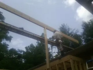 Carpenter setting a ridge beam over a new addition frame — Ice Dam Removal by Roofing Brothers in Waterboro