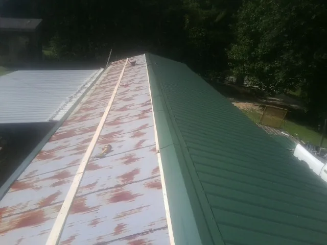 Old rusted panels beside newly installed green metal roofing — Wind Damage Roof Repair by Roofing Brothers in Waterboro