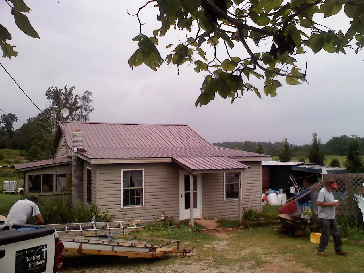 Crew finishing a mauve metal roof on a small farmhouse in Waterboro