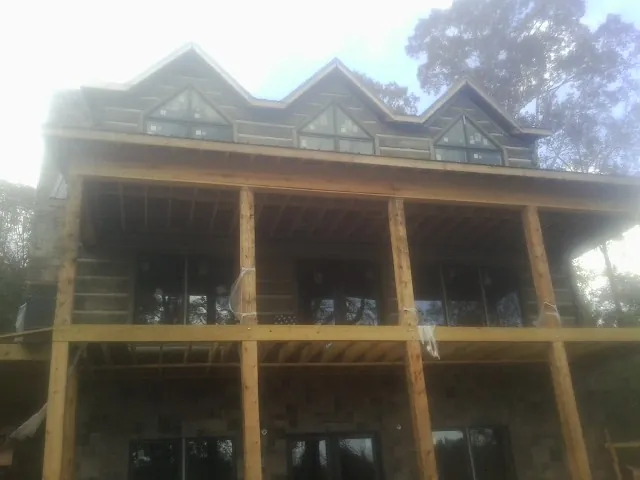 Dormers and porch framing on a large log home under construction — Roof Coating work by our crew in Waterboro