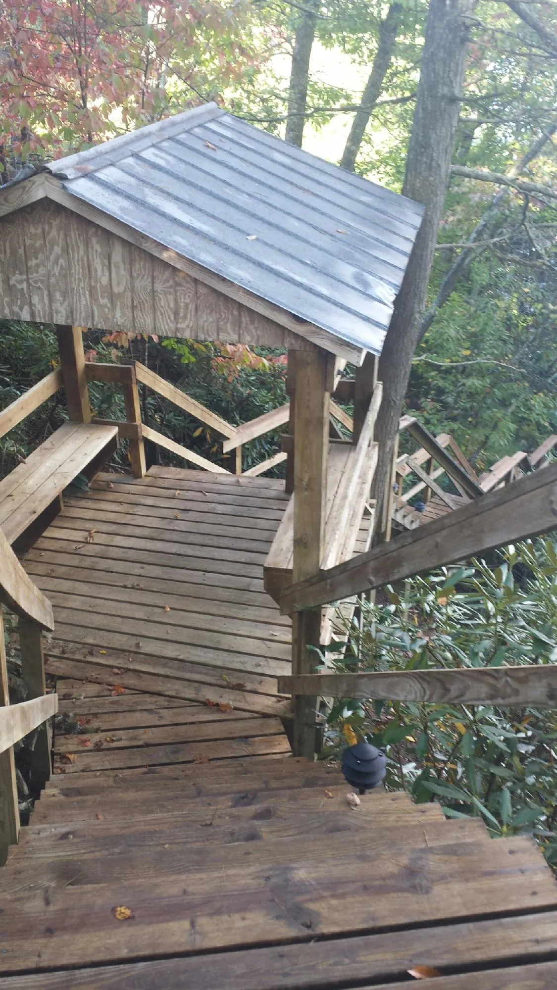 Metal roofed shelter over wooden steps on a wooded walkway — Skylight Repair & Installation work by our crew in Waterboro