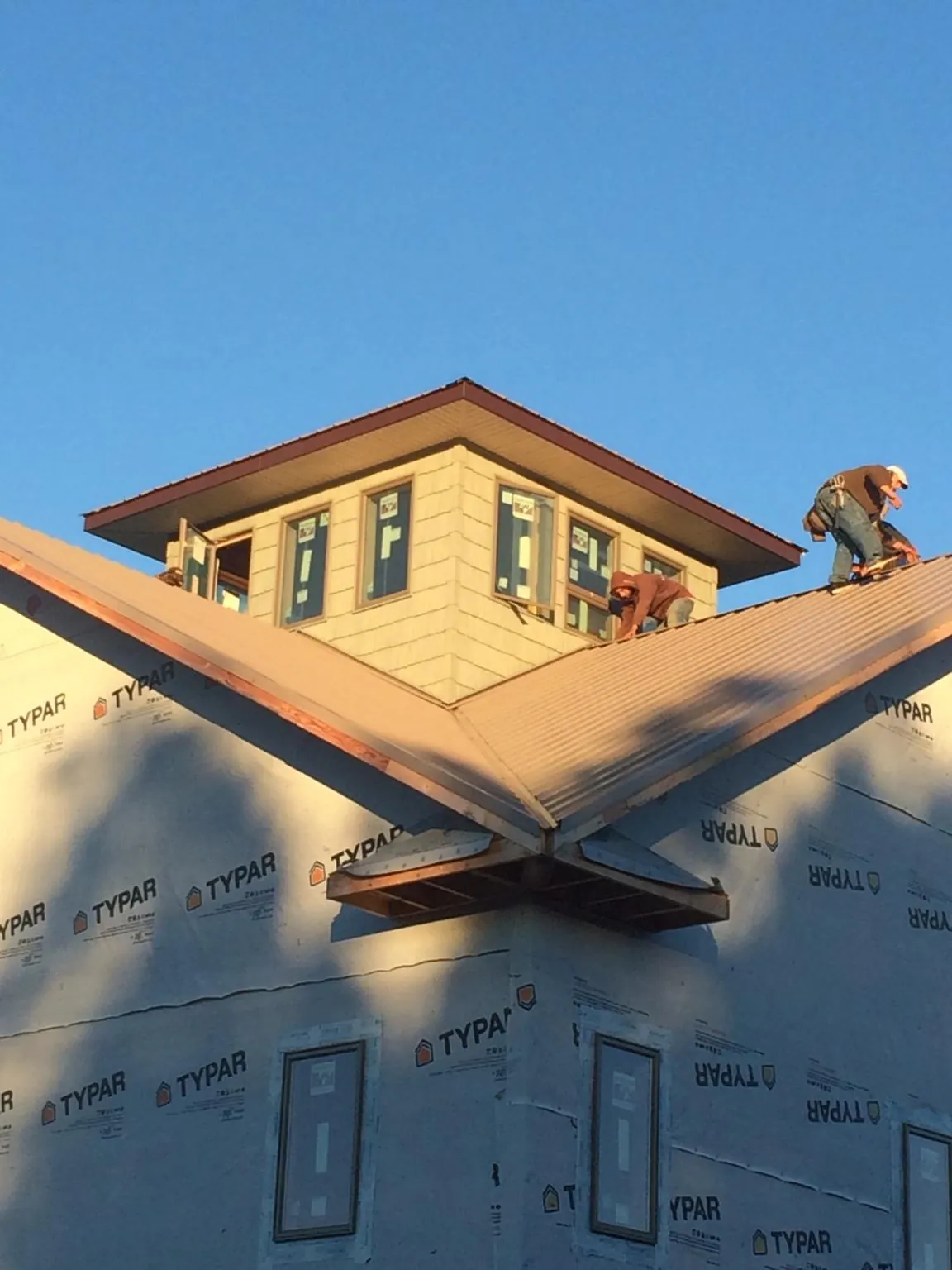 Roofers working around a rooftop cupola on a new metal roof at sunset — Roof Waterproofing in Waterboro by Roofing Brothers
